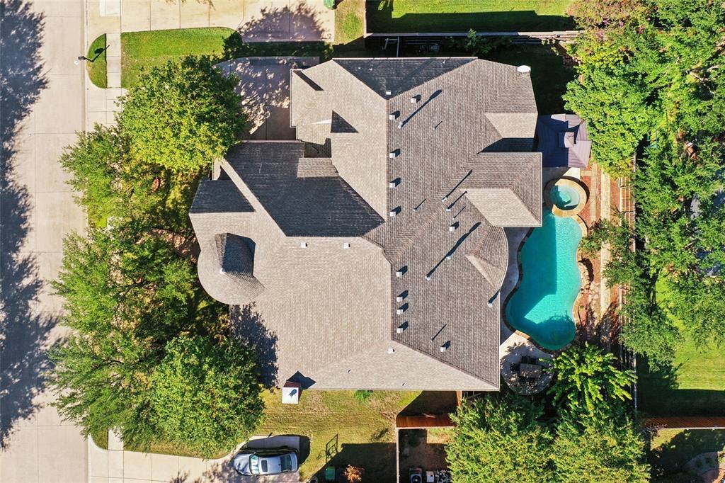 Asphalt shingle roofing over a multi-level structure with a curvilinear swimming pool and an integrated spa