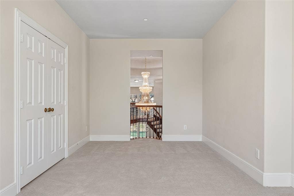 Recessed lighting, light neutral wall paint, carpet flooring, base molding, paneled door with brass hardware