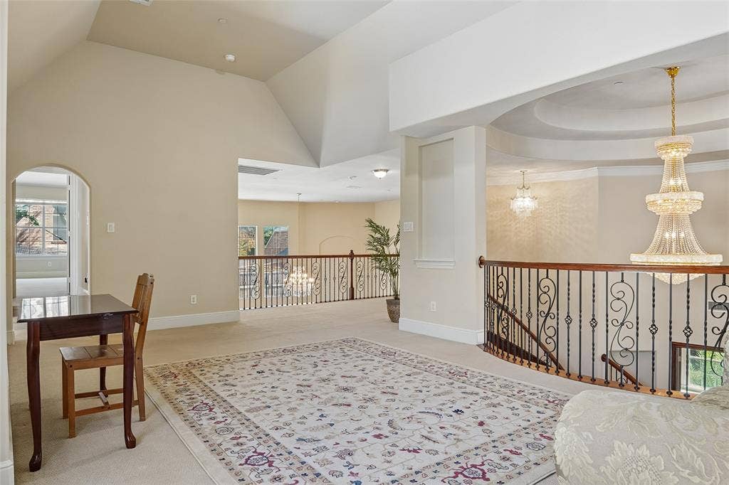 Architectural archway, wrought iron balusters, wood handrail, tray ceiling, and decorative chandelier