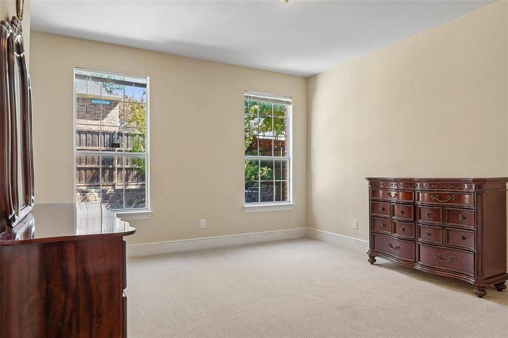 Carpeted room with neutral wall tones and two double-hung windows