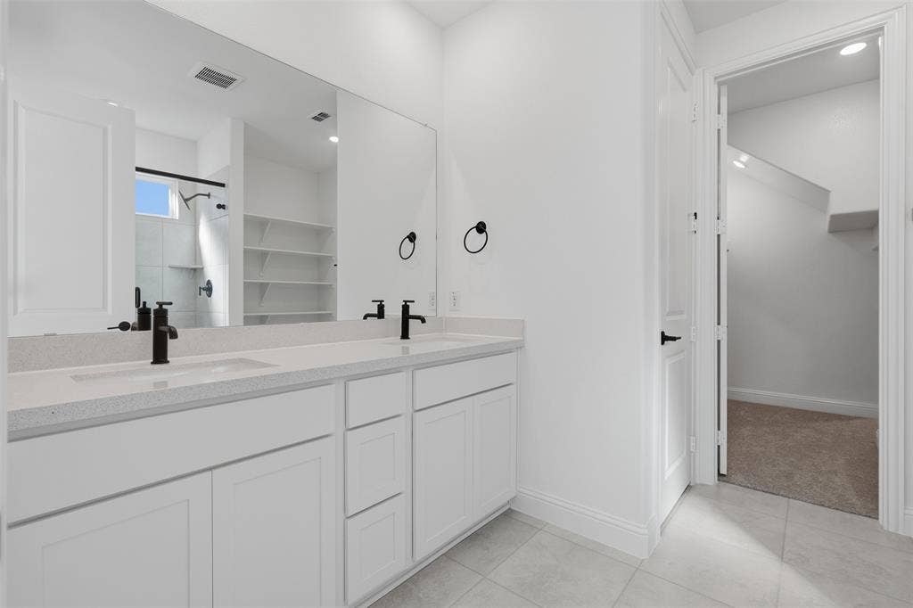 Dual vanity with white cabinetry, light-toned countertop, and matte black fixtures
