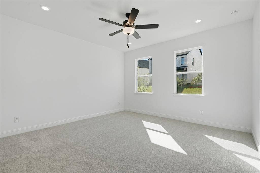 Recessed lighting, ceiling fan with integrated light, two windows, wall-to-wall carpeting, and white painted walls
