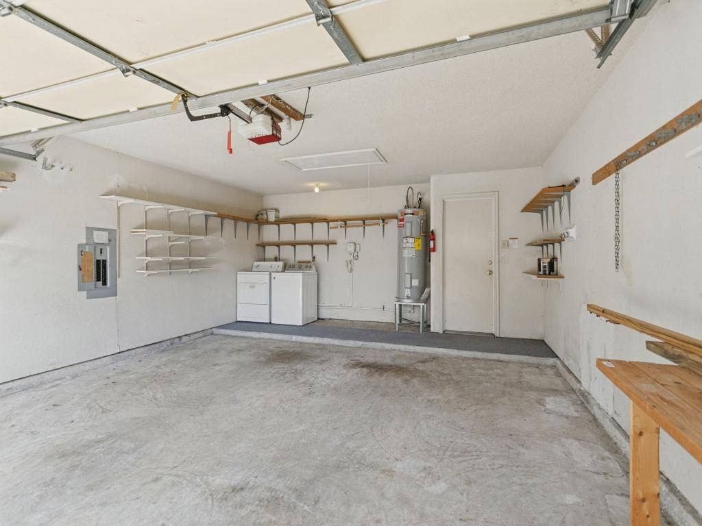 714 Bluebonnet Drive, Allen, TX 75002 Garage featuring integrated wall shelving, a concrete floor, an overhead door opener, and a designated utility area with washer and dryer, both convey with the house.