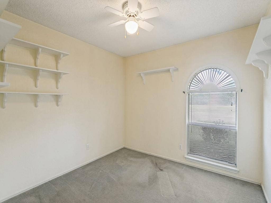 714 Bluebonnet Drive, Allen, TX 75002 Bedroom 1 with arched window, ceiling fan with integrated lighting, and multiple wall shelves