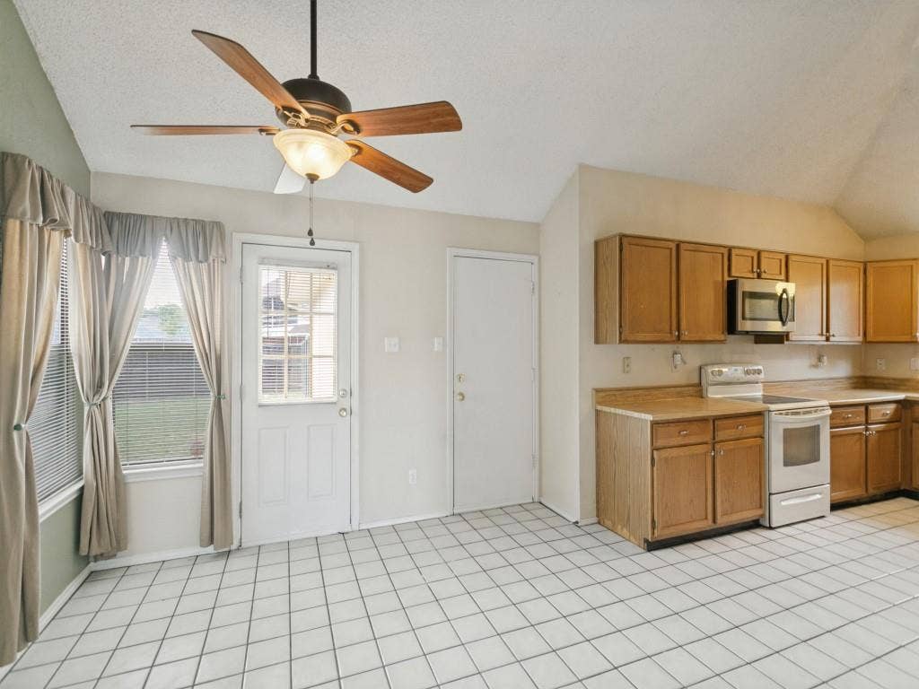 714 Bluebonnet Drive, Allen, TX 75002 Vaulted ceilings, tile flooring, wooden cabinetry, and a ceiling fan with integrated lighting