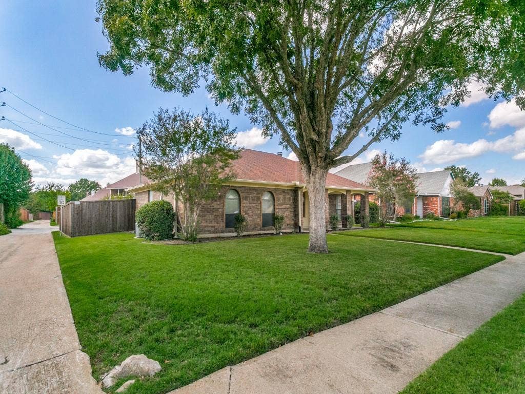 714 Bluebonnet Drive, Allen, TX 75002 Single-story brick exterior featuring a multi-gabled roofline, arched window detailing, and covered entryway.
