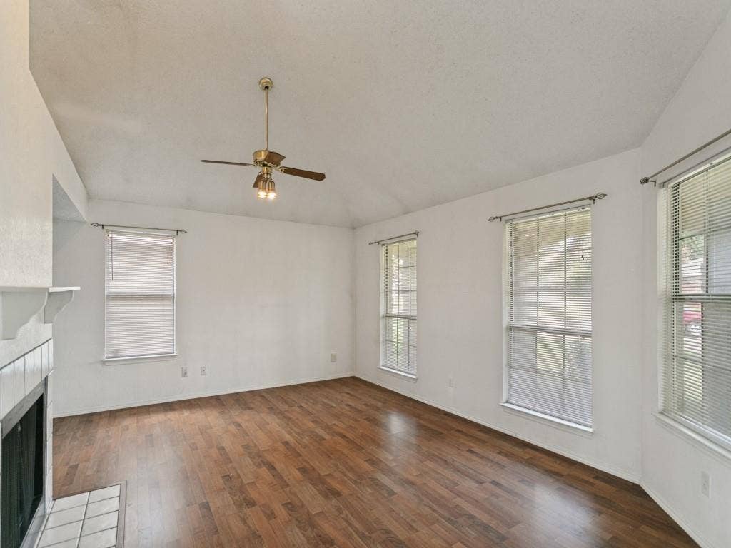 714 Bluebonnet Drive, Allen, TX 75002 Vaulted ceilings, wood-finish flooring, tiled fireplace surround, and multiple grid-pattern windows