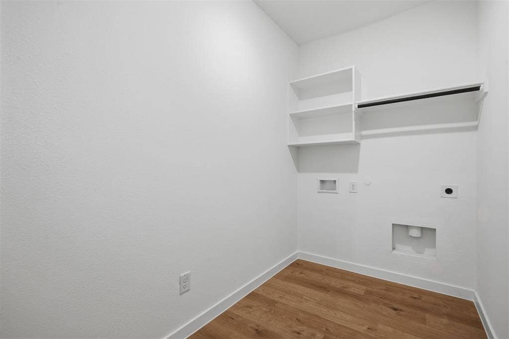 7117 Black Cherry Lane, McKinney, TX 75071 Laundry area featuring wood-finish flooring, white walls, and built-in shelving with a hanging rod