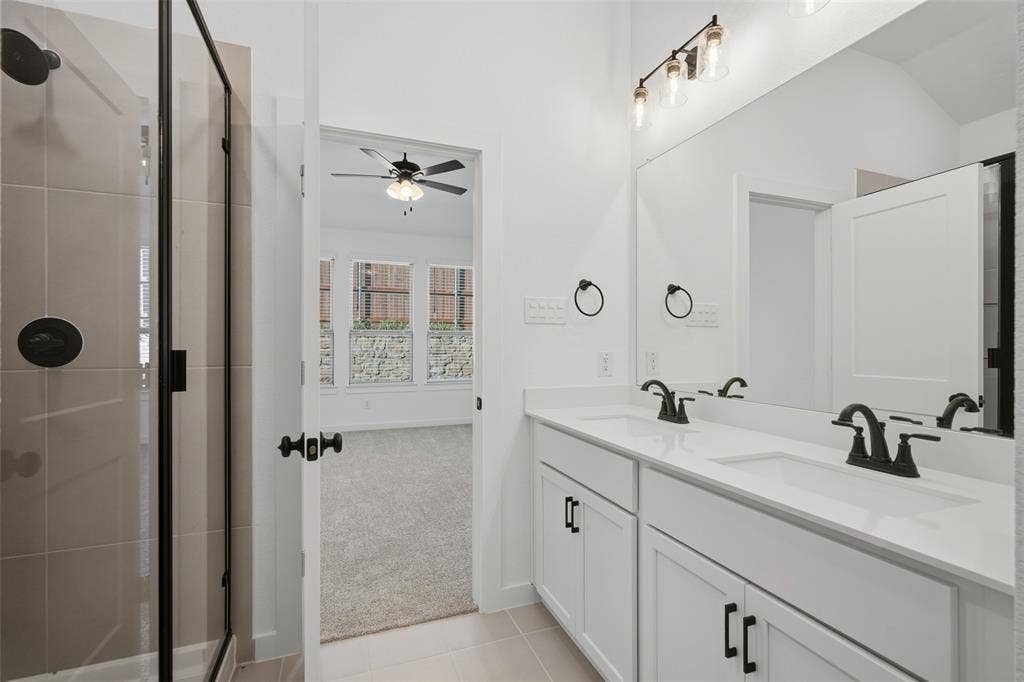 Dual vanity with white cabinetry, matte black hardware, and a large mirror