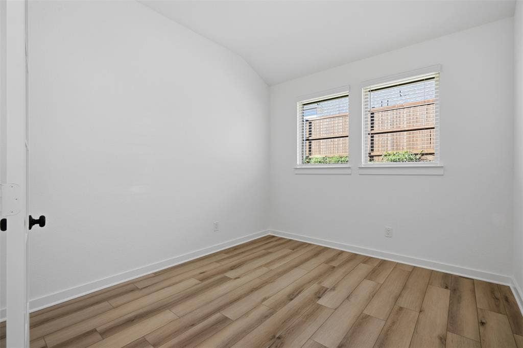Wood-finish flooring, white walls, and two windows with blinds