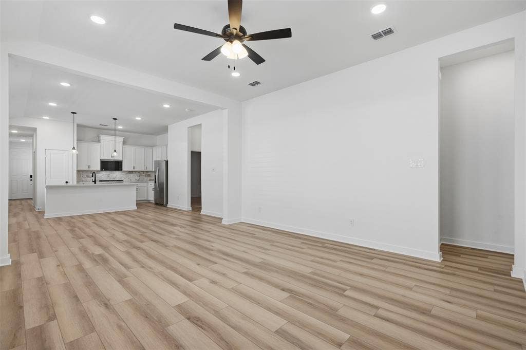 Spacious living area featuring wood-finish flooring, recessed lighting, and a ceiling fan