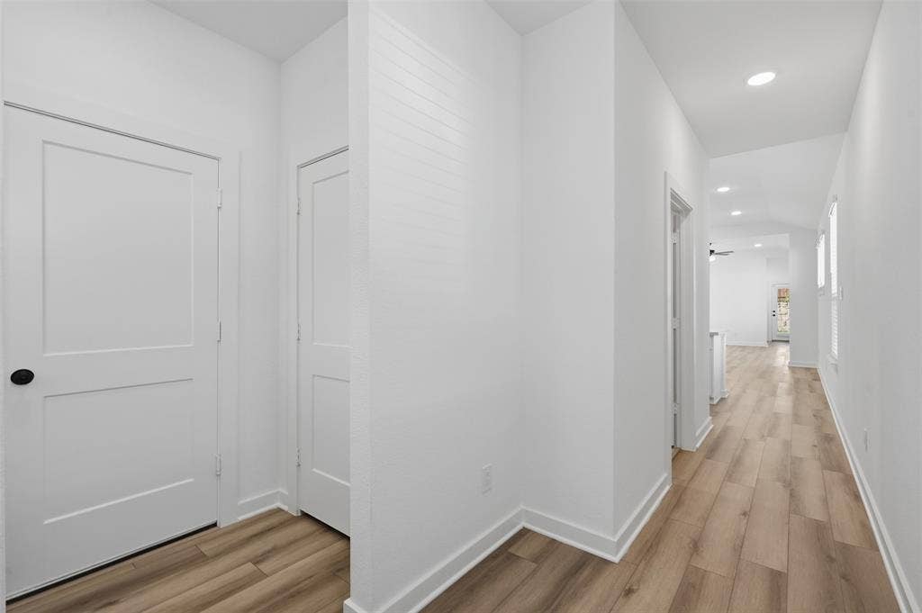 White interior walls, recessed ceiling lighting, wood-finish flooring, and white trim