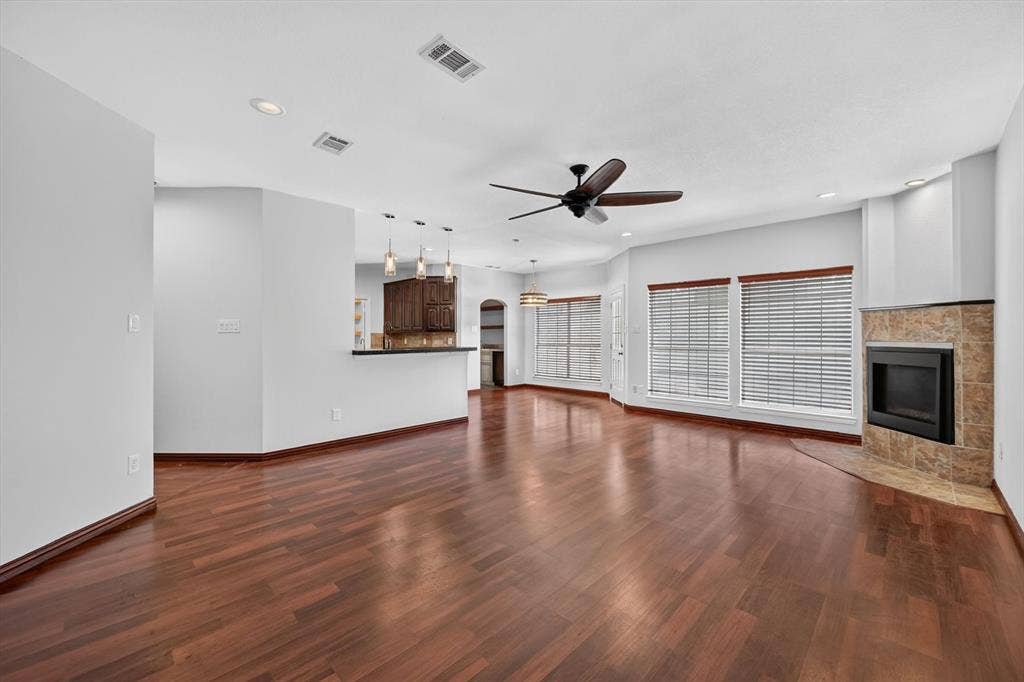 512 Renfro Court, Irving, TX 75063 Living space featuring wood-finish flooring, a corner fireplace with stone surround, recessed lighting, a ceiling fan, and a kitchen breakfast bar with pendant lighting