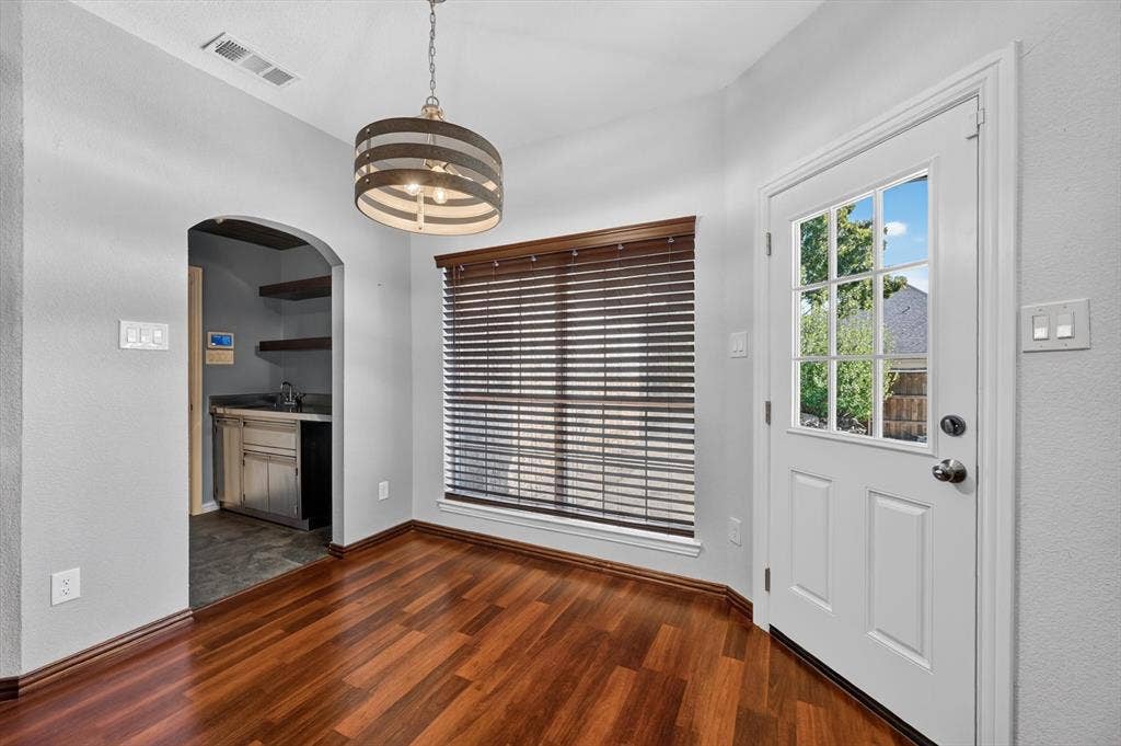 512 Renfro Court, Irving, TX 75063 Wood-finish flooring, arched entryway, drum-style pendant light, and exterior door with glass panes