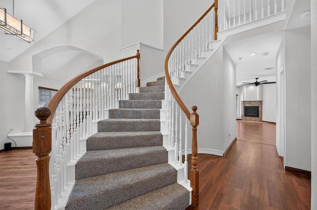 512 Renfro Court, Irving, TX 75063 Curved staircase with wood handrails, white balusters, and carpeted treads, featuring a two-story ceiling, recessed lighting, and wood-finish flooring
