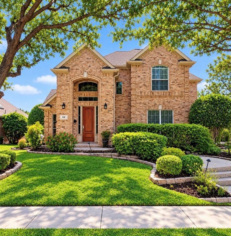512 Renfro Court, Irving, TX 75063 Two-story brick exterior featuring a prominent arched entryway, wood-panel door, stone-edged landscaping, and a multi-gabled roofline