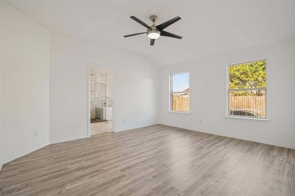 2815 Briarbrook Drive, Seagoville, TX 75159 Vaulted ceiling with a contemporary ceiling fan, wood-finish flooring, two windows, and an en-suite bathroom featuring a double vanity with ample lighting