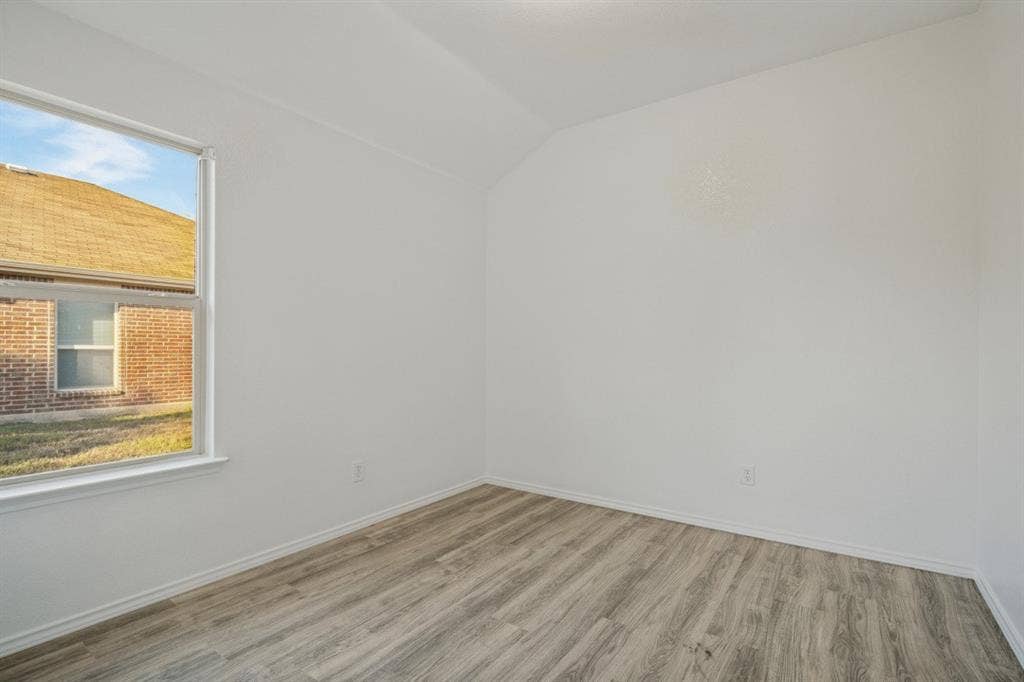 2815 Briarbrook Drive, Seagoville, TX 75159 Neutral paint palette with wood-finish flooring, a white window frame, and an angled ceiling