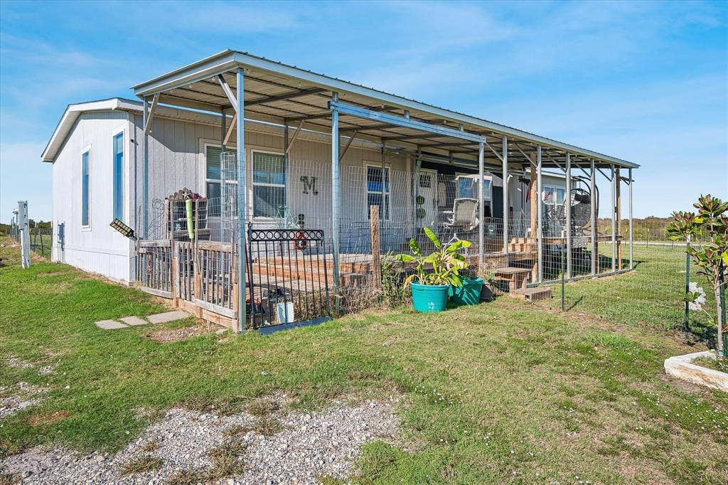 Front of home with covered porch and deck with fencing.