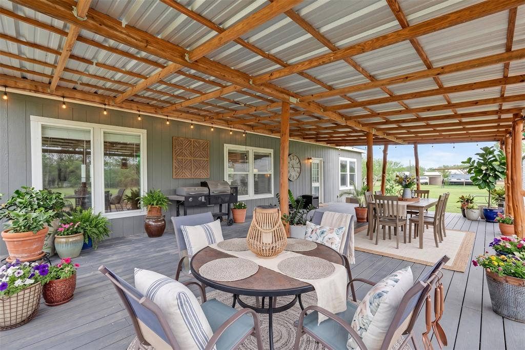 213 River Front Drive, Cedar Creek, TX 78612 Covered back porch with a wood beam and corrugated metal roof, gray plank flooring, and multiple windows