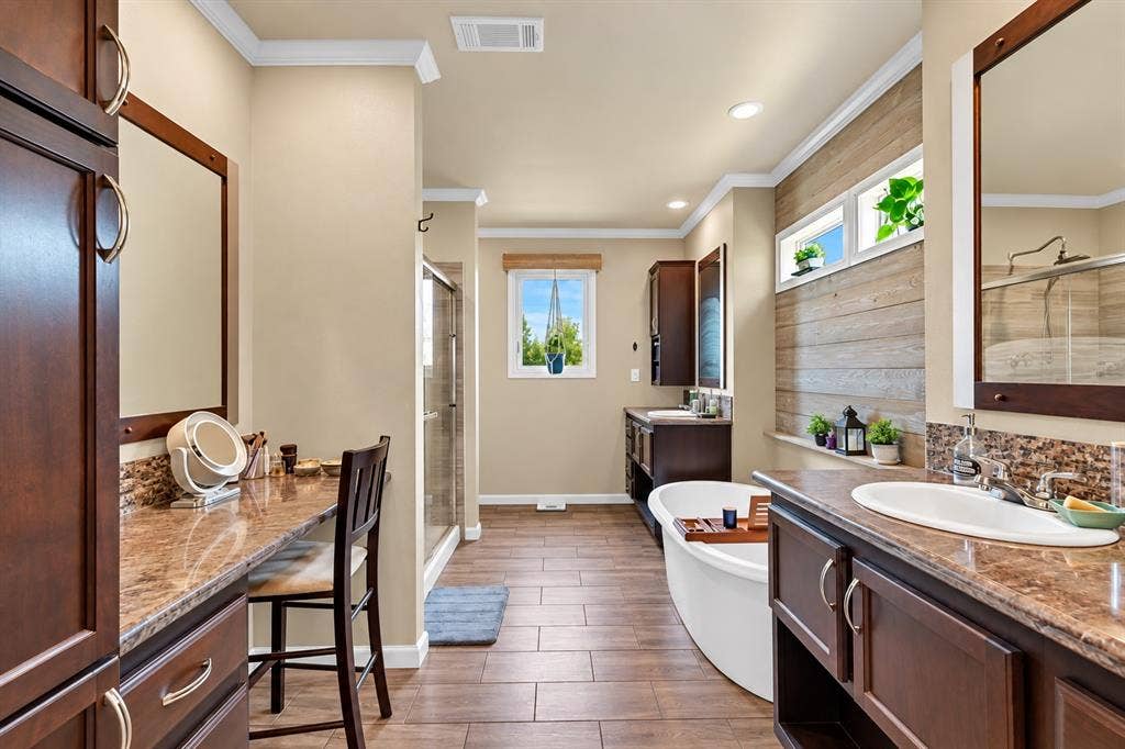 213 River Front Drive, Cedar Creek, TX 78612 Spacious bathroom featuring wood-finish flooring, a freestanding soaking tub, a glass-enclosed shower, dual vanity sinks, and ample cabinetry