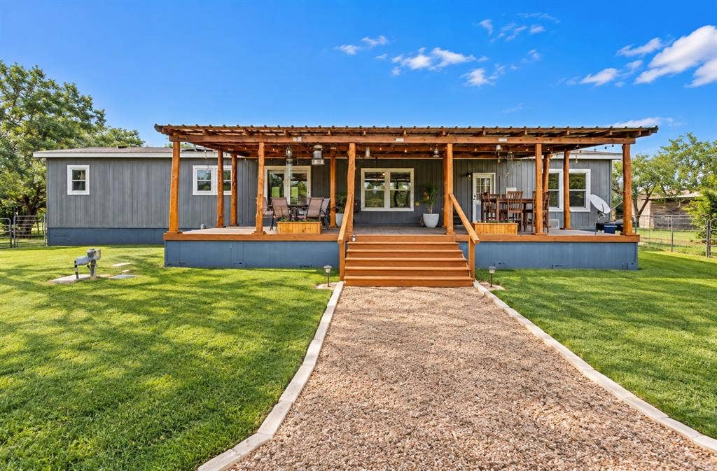 213 River Front Drive, Cedar Creek, TX 78612 Exterior featuring a broad wood deck, wood pergola, and gravel pathway