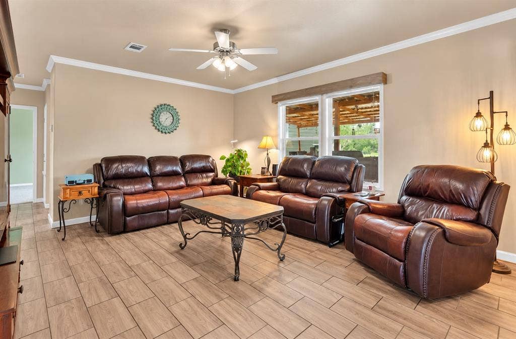 213 River Front Drive, Cedar Creek, TX 78612 Living area featuring wood-finish flooring, a ceiling fan with integrated lighting, and crown molding