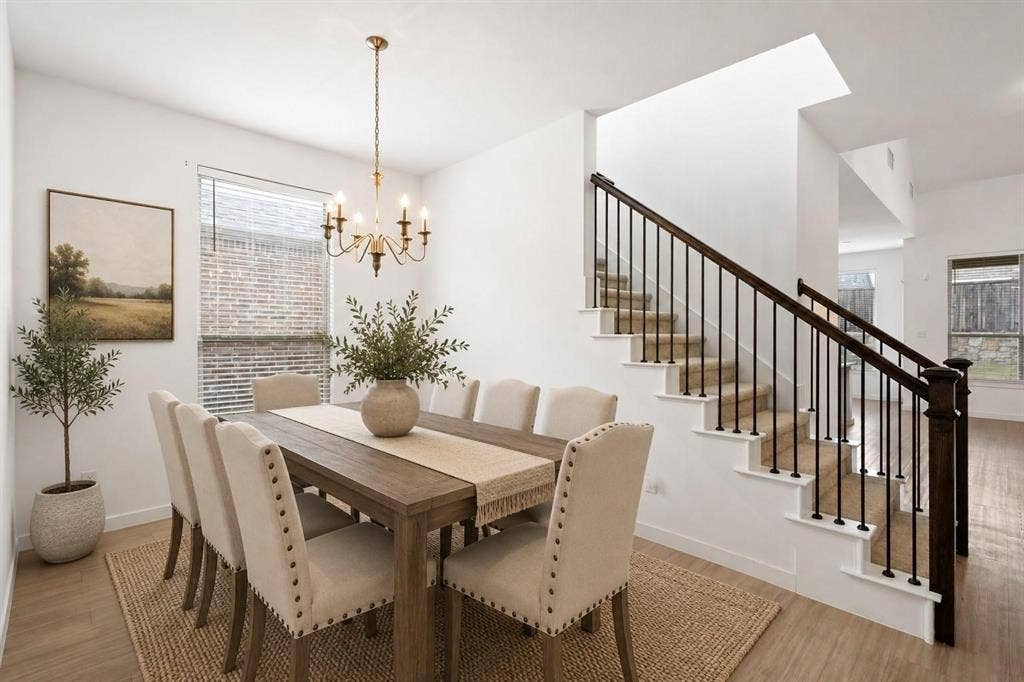 2466 San Marcos Drive, Forney, TX 75126 Open-concept interior featuring wood-finish flooring, a multi-arm chandelier, and a staircase with dark wood handrails and black metal balusters