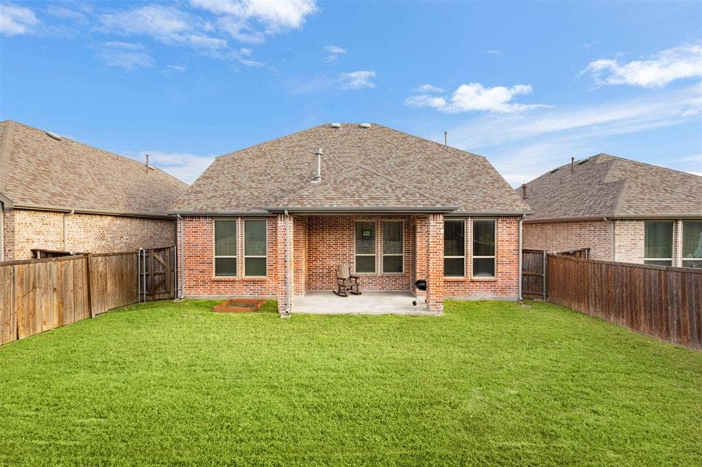 2466 San Marcos Drive, Forney, TX 75126 Full brick exterior with a covered rear patio, expansive grass lawn, and wood privacy fencing