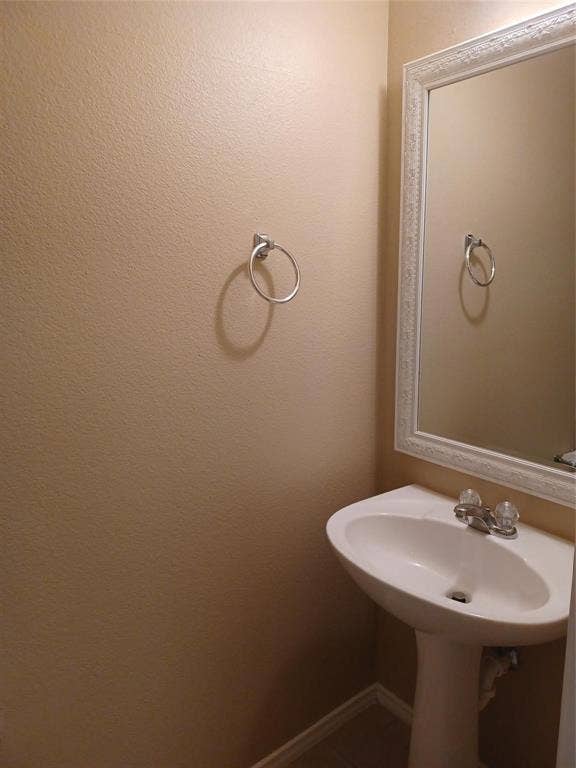 Pedestal sink with dual-handle faucet, framed wall mirror, and wall-mounted towel ring