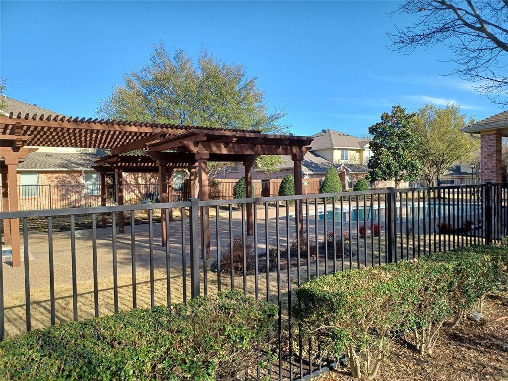Expansive outdoor space featuring a pool, surrounding patio, and a slatted pergola structure