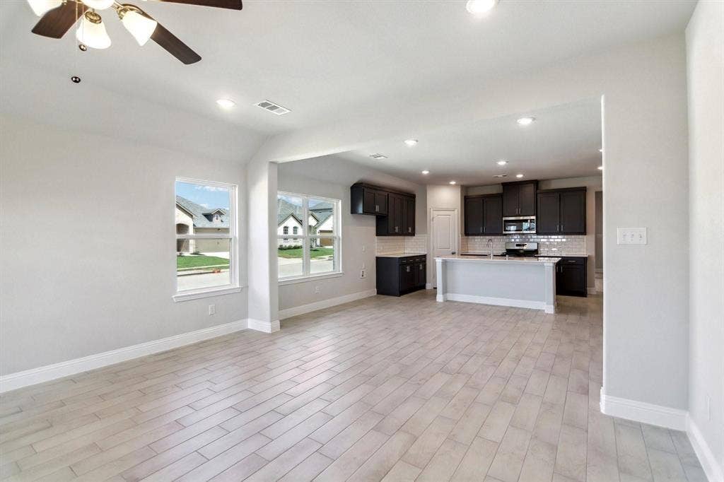 Recessed lighting, wood-finish flooring, ceiling fan, dark wood cabinetry, and a kitchen island with a light-toned countertop