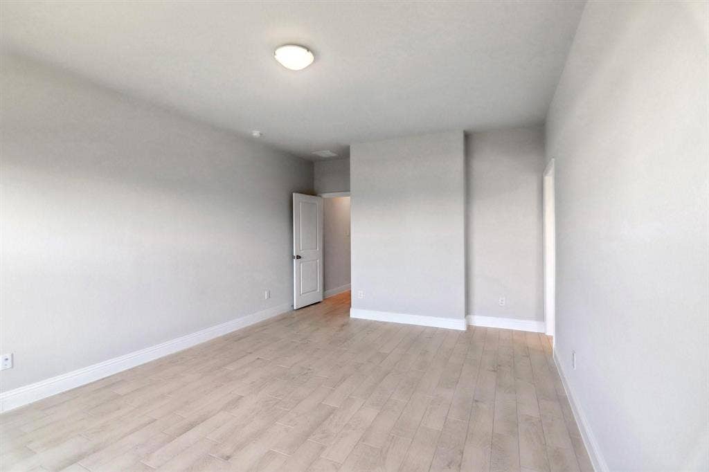 Spacious room featuring light wood-finish flooring, neutral wall paint, and recessed lighting
