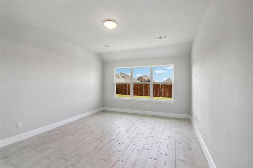 Bright room featuring large window, light-toned walls, and tile flooring