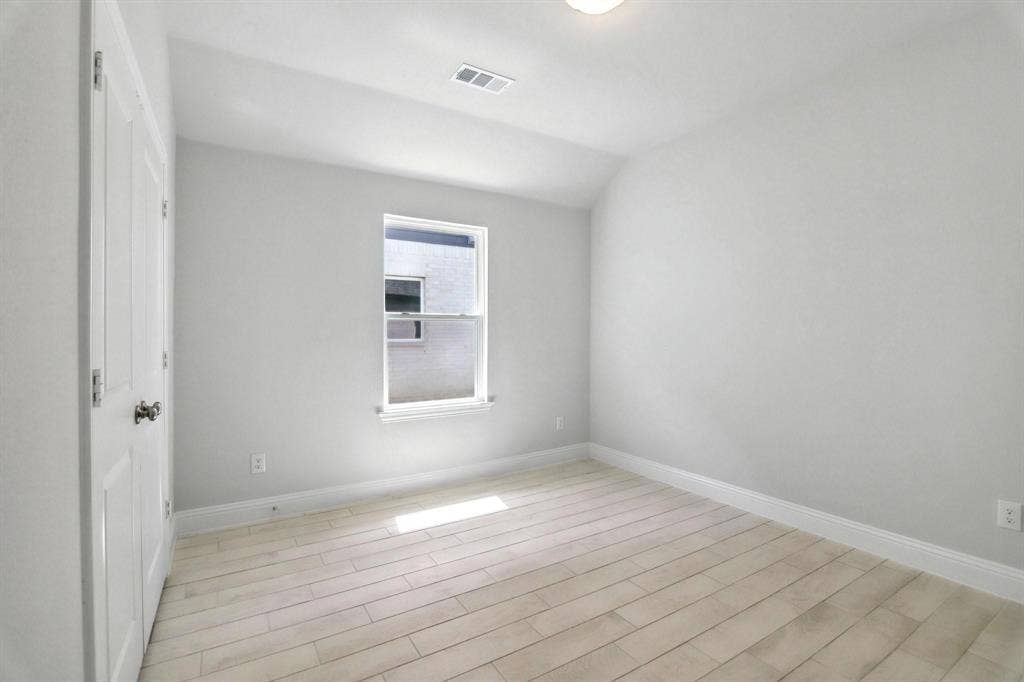 Light-toned wood-finish flooring, white walls, and a single window with a white frame