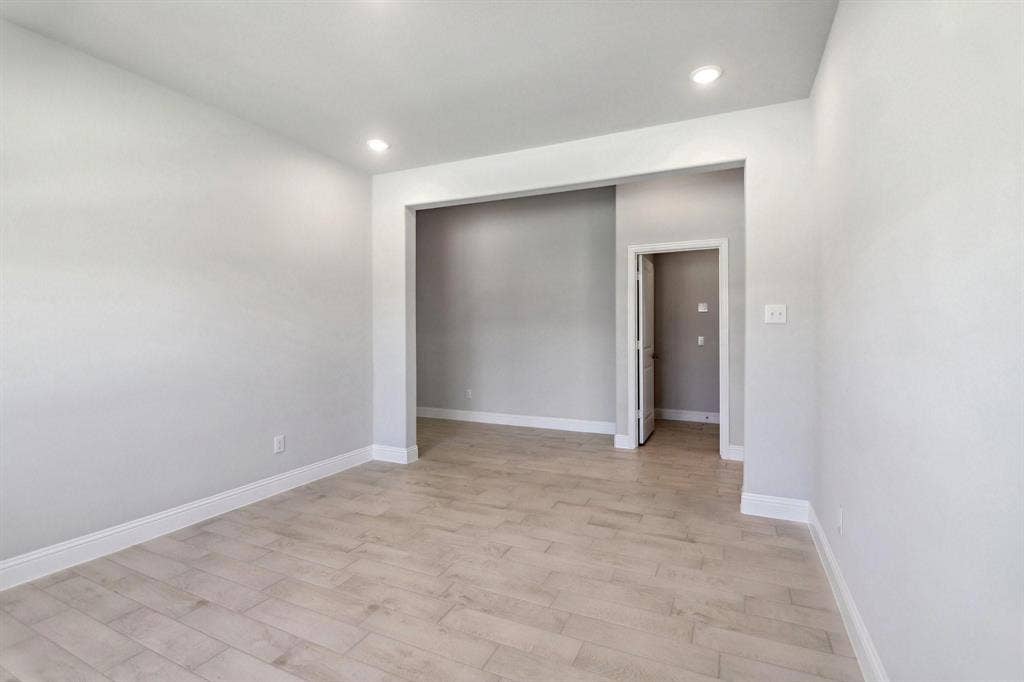 Recessed lighting illuminates the space, featuring wood-finish flooring and light-toned walls