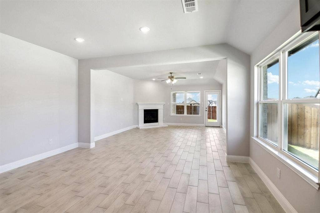 Recessed lighting, wood-finish flooring, white mantel, ceiling fan, and multiple windows