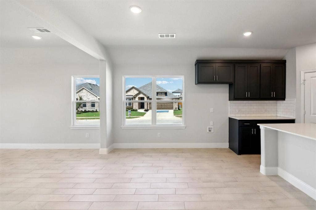 Recessed lighting, wood-finish flooring, white walls, dark cabinetry, and a white subway tile backsplash