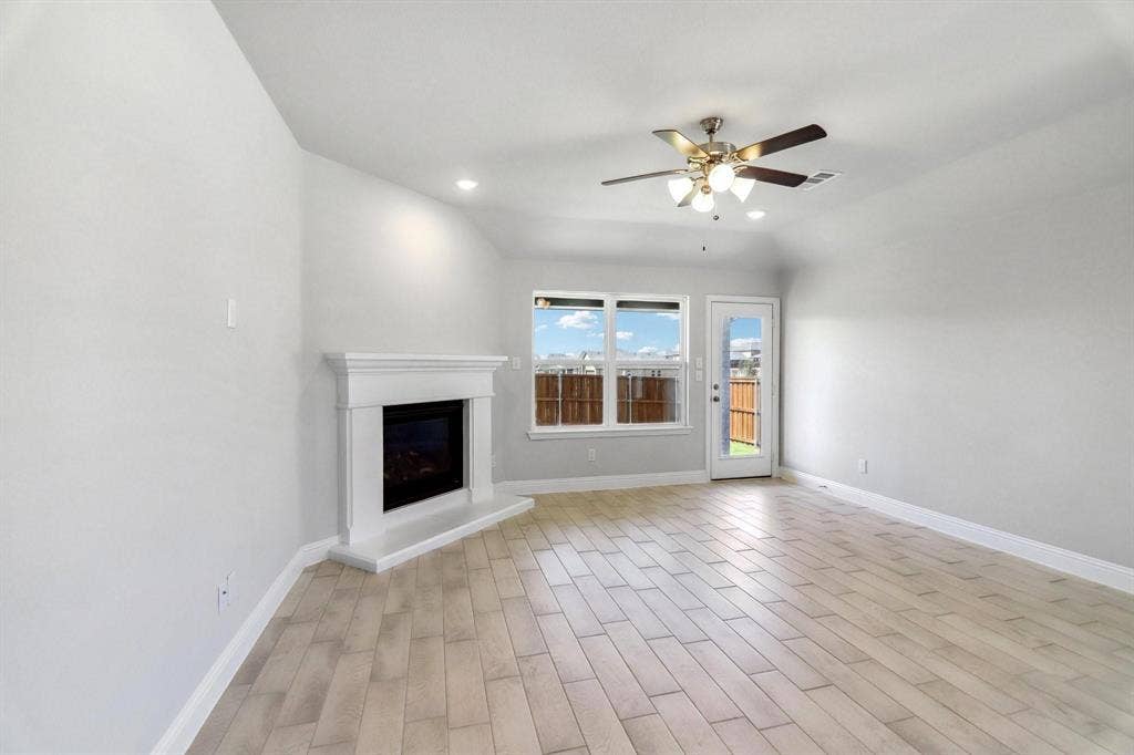 Living area featuring wood-finish flooring, a white fireplace with mantel, recessed lighting, and a ceiling fan with light kit