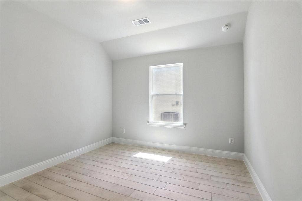 Neutral tone wall paint, wood-finish flooring, single window, and white trim molding