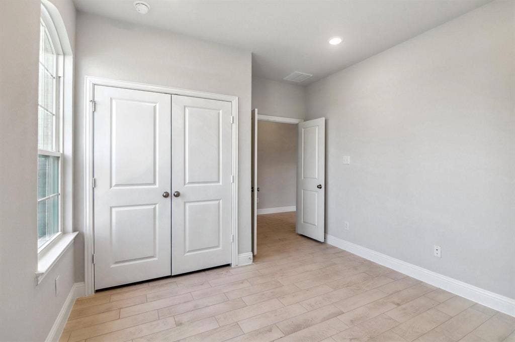 Recessed lighting, wood-finish flooring, arched window, paneled doors, and light gray walls