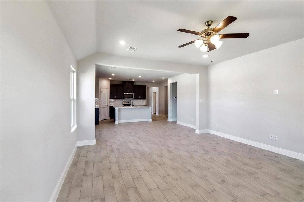 Open-concept living space with wood-finish flooring, recessed lighting, and a ceiling fan