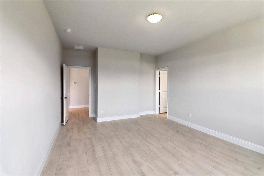 Light wood-finish flooring with white baseboards and light gray walls
