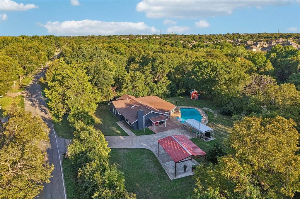 500 Spinner Road, DeSoto, TX 75115 Expansive property featuring a private swimming pool, covered outdoor living space, and a red metal roof carport
