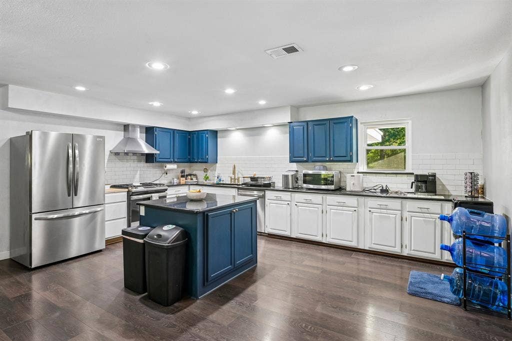 500 Spinner Road, DeSoto, TX 75115 Kitchen featuring dark wood-finish flooring, a central island with a dark countertop, white subway tile backsplash, recessed lighting, and stainless steel appliances