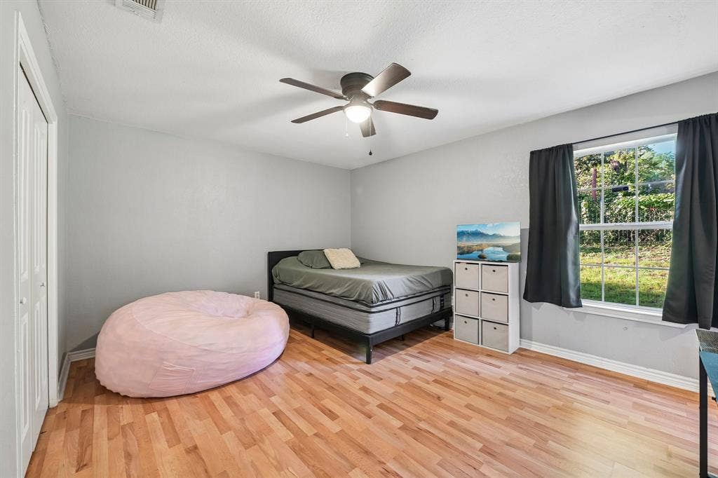 500 Spinner Road, DeSoto, TX 75115 Wood-finish flooring, ceiling fan, white bi-fold closet doors, and a window with a natural outdoor backdrop