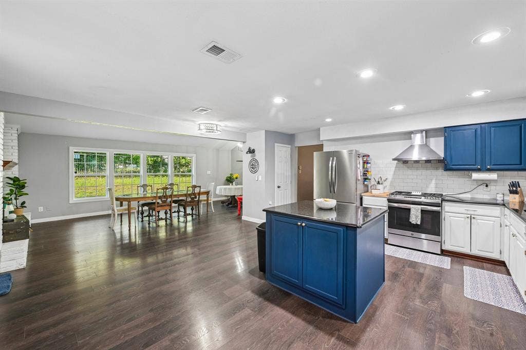 500 Spinner Road, DeSoto, TX 75115 Open-concept living area featuring wood-finish flooring, a kitchen island with storage, stainless steel appliances, and large windows