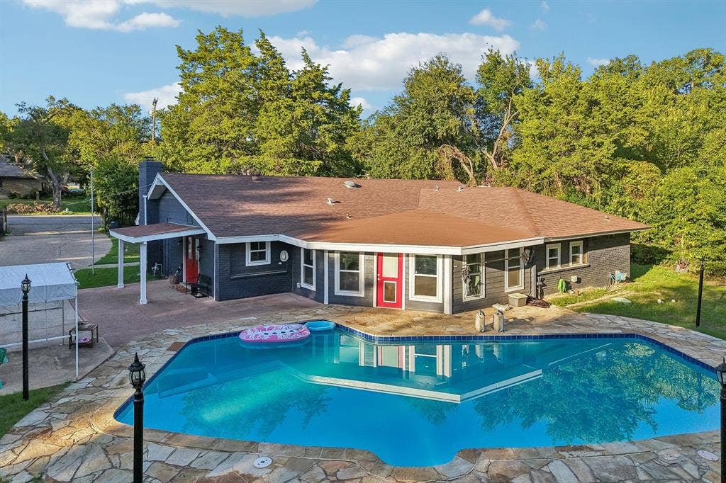 500 Spinner Road, DeSoto, TX 75115 Outdoor swimming pool with integrated sun ledge, stone patio surround, and a covered entry