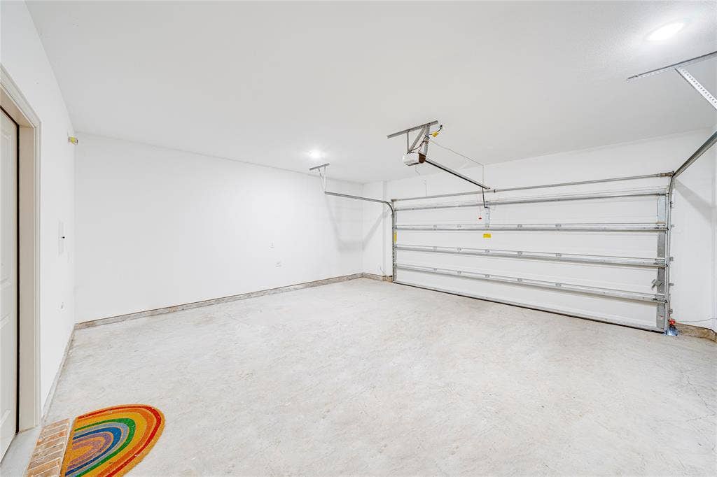 8888 Samara Street, Frisco, TX 75035 Attached garage with a white sectional door, concrete flooring, and overhead lighting