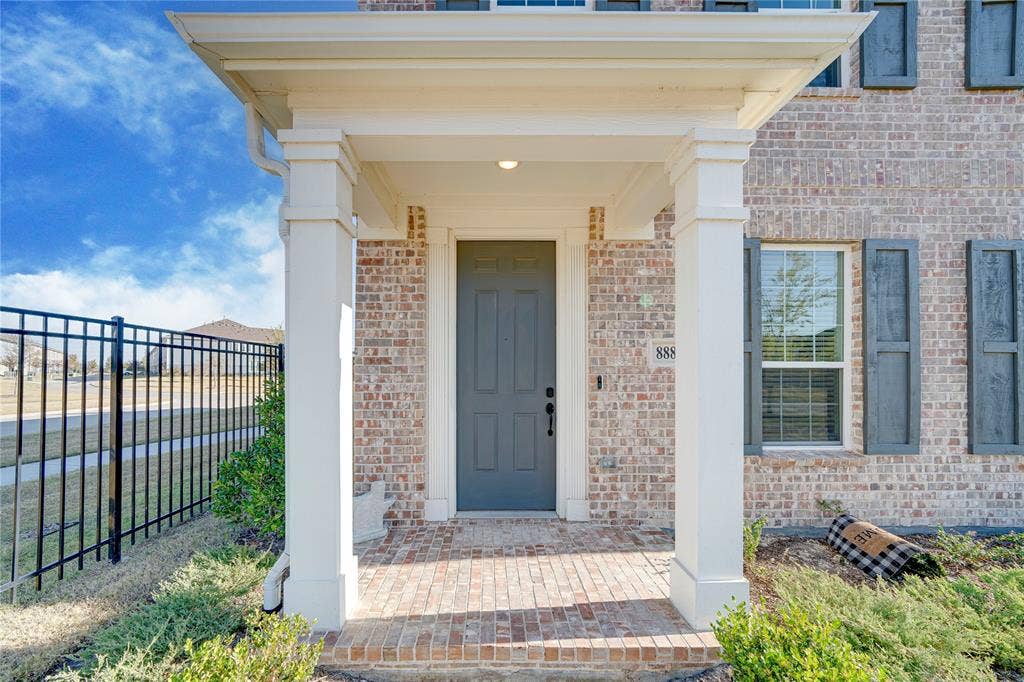 8888 Samara Street, Frisco, TX 75035 Brick exterior with a covered entry, decorative shutters, and an iron fence